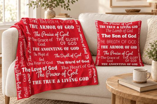 Red Attributes of God throw blanket and matching pillow with white faith-inspired lettering on a cream sofa in a sunlit living room.