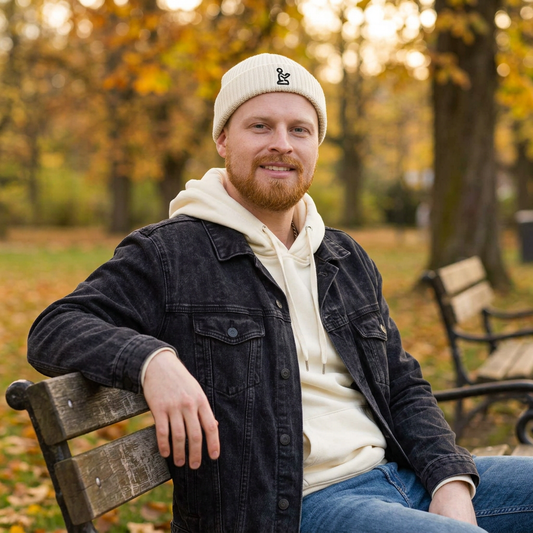 Man wearing the ecru beanie while sitting on a park bench