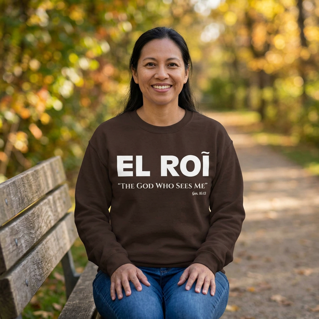 Woman seated on a park bench wearing the brown El Roi sweatshirt