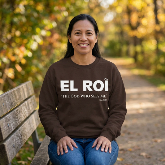 Woman seated on a park bench wearing the brown El Roi sweatshirt